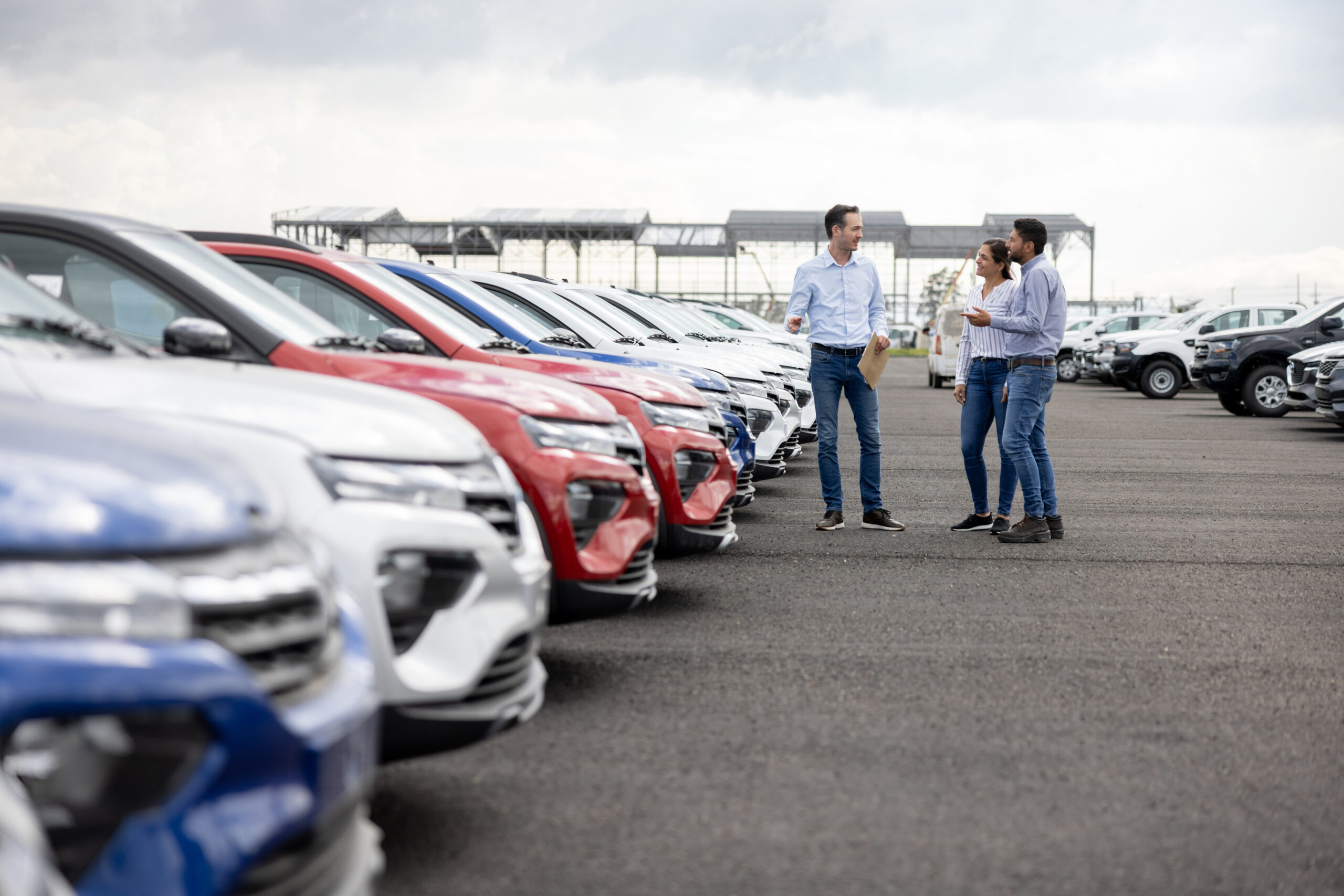Salesman showing cars to a couple at the dealership Come l'implementazione di soluzioni tecnologiche avanzate ha trasformato un'azienda di noleggio auto